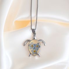 The playful and artistic Forget Me Not Sea Turtle Necklace is a must-have for any beach lover's summer collection. Surprise yourself or someone special with this stunning nautical necklace.Details:Real Forget Me Not Flowers in ResinSea Turtle: Eco-friendly AlloyBox Chain: Stainless Steel, 20" with a 2" Extension Sunshine on your neck, the ocean in your ears. Discover GoBeachy jewelry - where summer never fades. Dive into sun-kissed sparkle, where quality meets coastal charm. GoBeachy jewelry isn Ocean-inspired Necklaces For Summer Gifts, Ocean-inspired Necklaces As Summer Gifts, Ocean-inspired Adjustable Necklace As A Gift, Adjustable Ocean-inspired Necklace For Gifts, Adjustable Ocean-inspired Necklace For Gift, Ocean-inspired Nickel Free Pendant Necklace, Ocean-inspired Nickel-free Pendant Necklace, Summer Nickel Free Necklaces As Gift, Nickel-free Necklaces As Summer Gifts