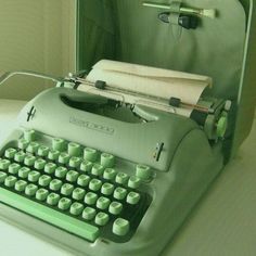 an old fashioned typewriter sitting on top of a white table next to a mirror