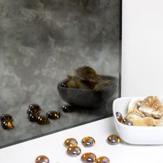 a bowl filled with lots of different types of beads next to a mirror and some rocks