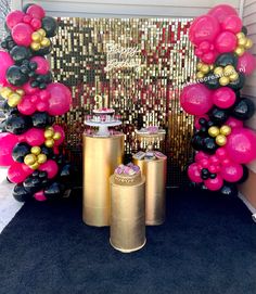 balloons and decorations are on display in front of a gold foil backdrop with black, pink, and white balloons