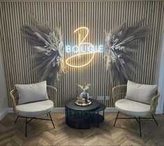 two chairs sitting next to each other in front of a wall with a neon sign