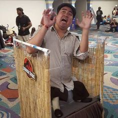 a man sitting on top of a chair with his hands in the air while making an obscene gesture