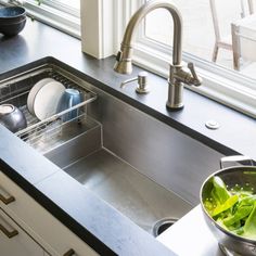 a stainless steel kitchen sink with green salad in it