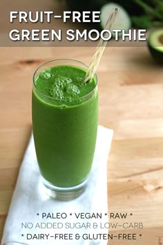 a green smoothie with a straw in it on a napkin next to an avocado