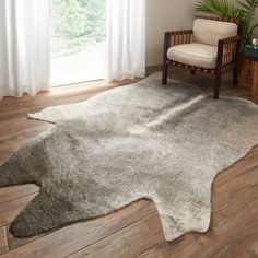 a living room area with a chair and rug on the wooden floor, along with a large window