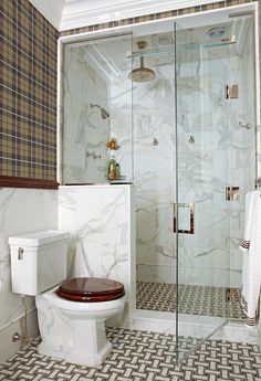 a white toilet sitting next to a walk in shower under a glass enclosed shower stall