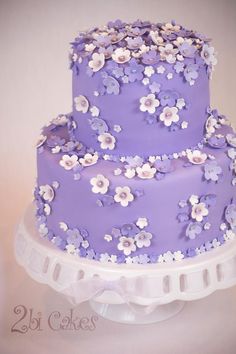 a purple and white wedding cake with flowers on it