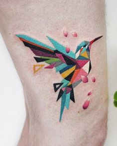 a colorful hummingbird tattoo on the leg with dots and sprinkles around it