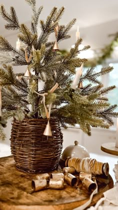 a small christmas tree in a wicker basket on top of a table with candles