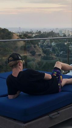 a man laying on top of a blue mattress in front of a cityscape