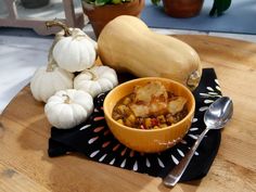 a bowl filled with food sitting on top of a wooden table next to pumpkins