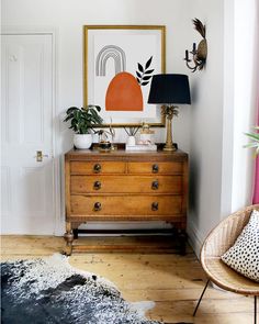 a room with a wooden dresser, black and white rug, and a painting on the wall