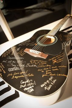 a guitar with many autographs on it