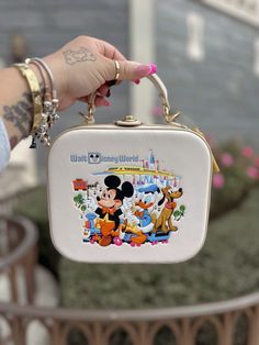 a person holding a small purse with mickey mouse on it