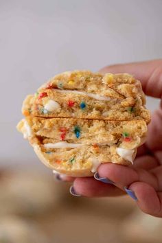 a hand holding a cookie with white frosting and sprinkles