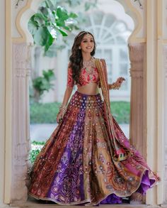 a woman in a purple and gold lehenga is posing for the camera with her hands on her hips