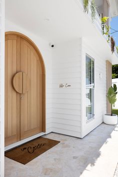 a white house with a large wooden door and planters on the outside wall next to it