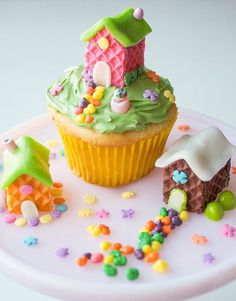 a cupcake with green frosting and decorations on it sitting on top of a plate