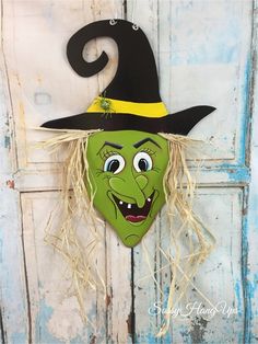 a green witch mask hanging on the side of a door