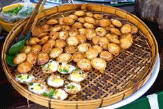 a basket filled with fried food next to chopsticks and bowls full of other foods