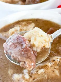 a spoon full of soup with meat in it