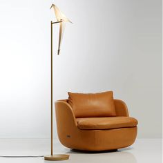 a chair with a lamp on top of it next to a couch and floor lamp