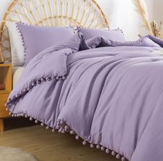 a bed covered in purple sheets and pillows