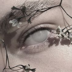 a woman with flowers in her hair is looking at the camera while she's wearing makeup