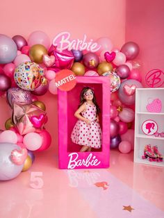 a barbie doll in a pink box surrounded by balloons