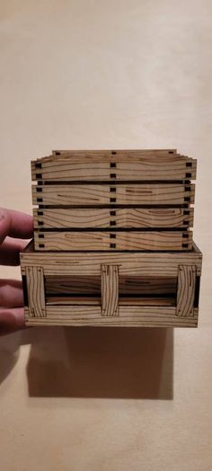 a hand holding a small wooden box on top of a table