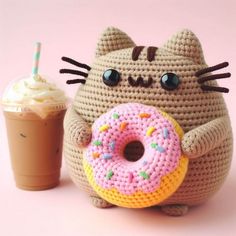 a crocheted cat holding a donut and a cup of coffee with a straw in it