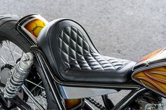 a close up of a motorcycle seat on the back of a bike with an orange and yellow design