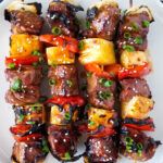 skewered meat and vegetables on a white plate