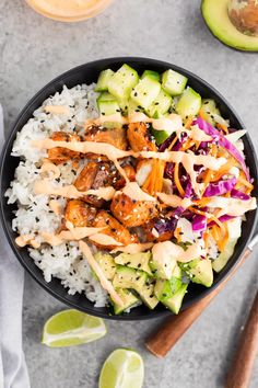 a bowl filled with rice, chicken and veggies next to sliced avocado