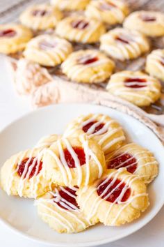 some cookies are sitting on a white plate and one is covered in icing with raspberries