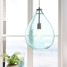 a light bulb hanging from a window next to a potted plant on a table