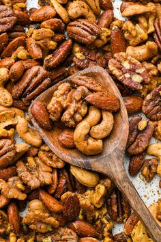 a wooden spoon filled with nuts on top of a table