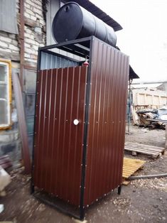 an outhouse with a large metal barrel on top