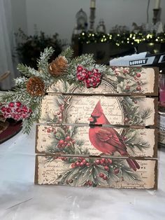 a wooden box with a cardinal on it and pine cones in the corner, sitting on top of a table