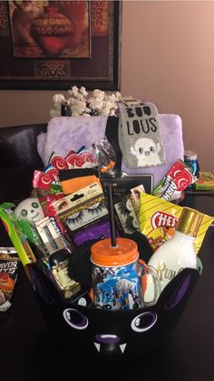 a black cat shaped basket filled with snacks and candy sits on top of a table