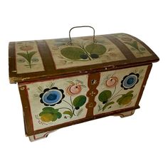 an old wooden box with flowers painted on it's sides and handles, sitting against a white background