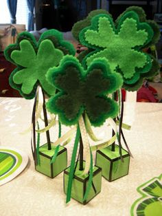 four leaf clovers are sitting in small vases on a table with other decorations