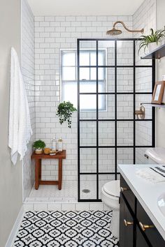 a white tiled bathroom with black and white tile flooring, an open shower door and window