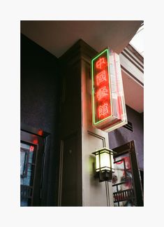 a red and green sign hanging from the side of a building next to a doorway