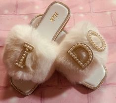 a pair of white slippers with pearls on the bottom and letters that spell d