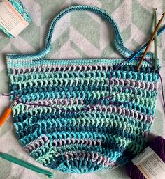 a crocheted purse with yarn and knitting needles