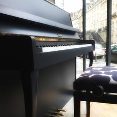 a black piano sitting in front of a window