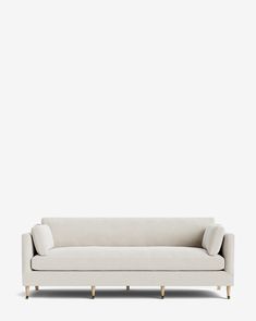 a white couch sitting on top of a wooden floor next to a wall with a light colored background