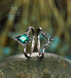 two silver rings with green stones on top of each other, sitting on a rock