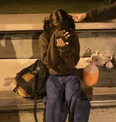 a woman sitting on a bench with her head in her hands, and another person standing next to her